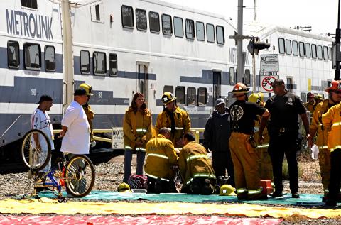 Firefighters and passengers in front of train.