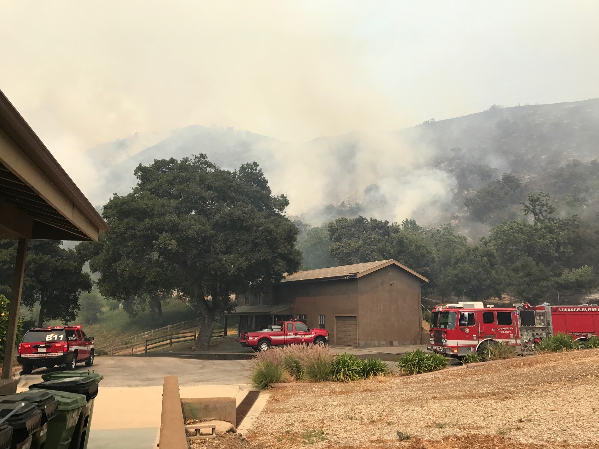 Fire engines defending home against approaching brush fire