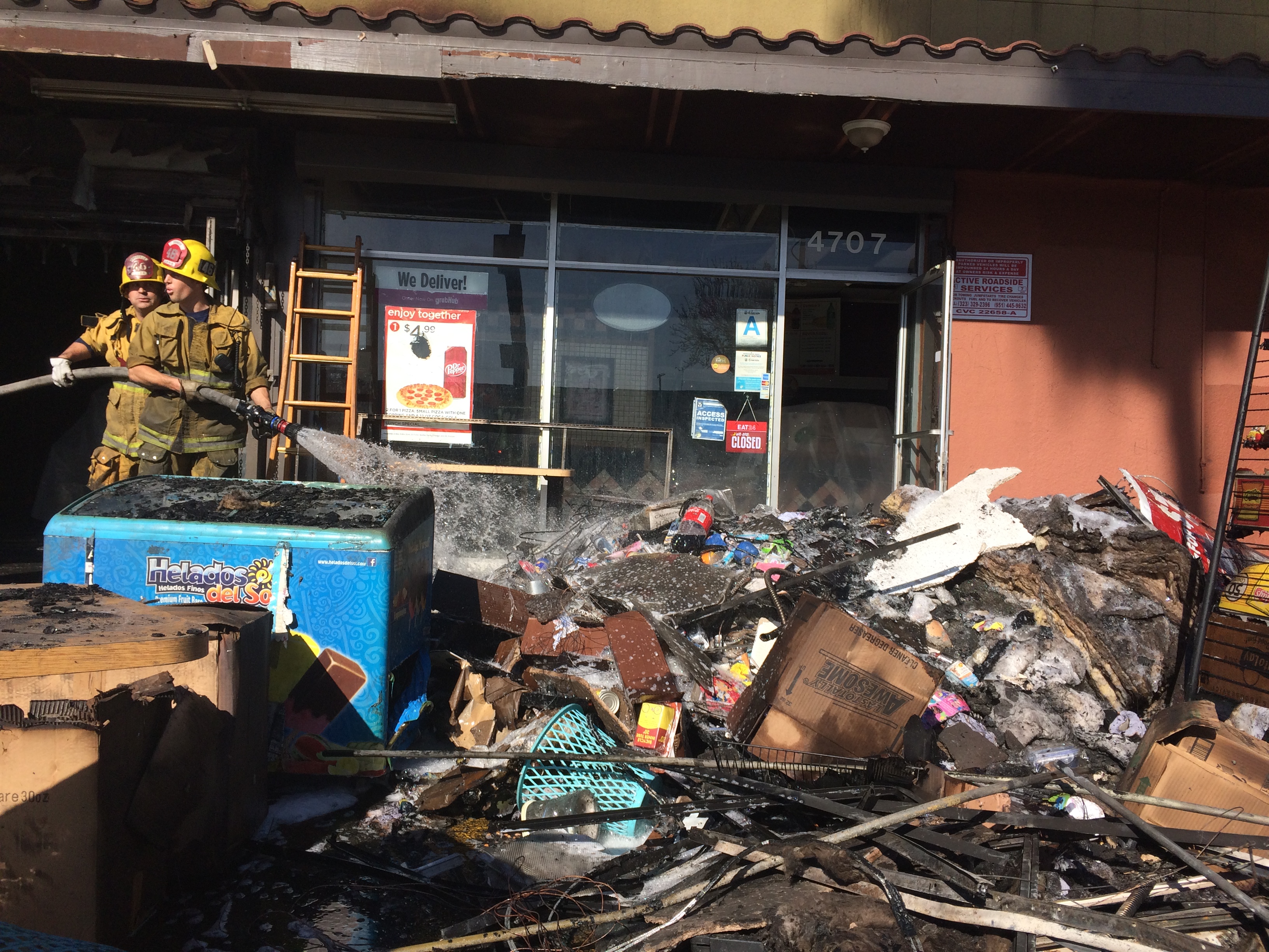 Overhaul pile outside of strip mall unit heavily damaged by fire