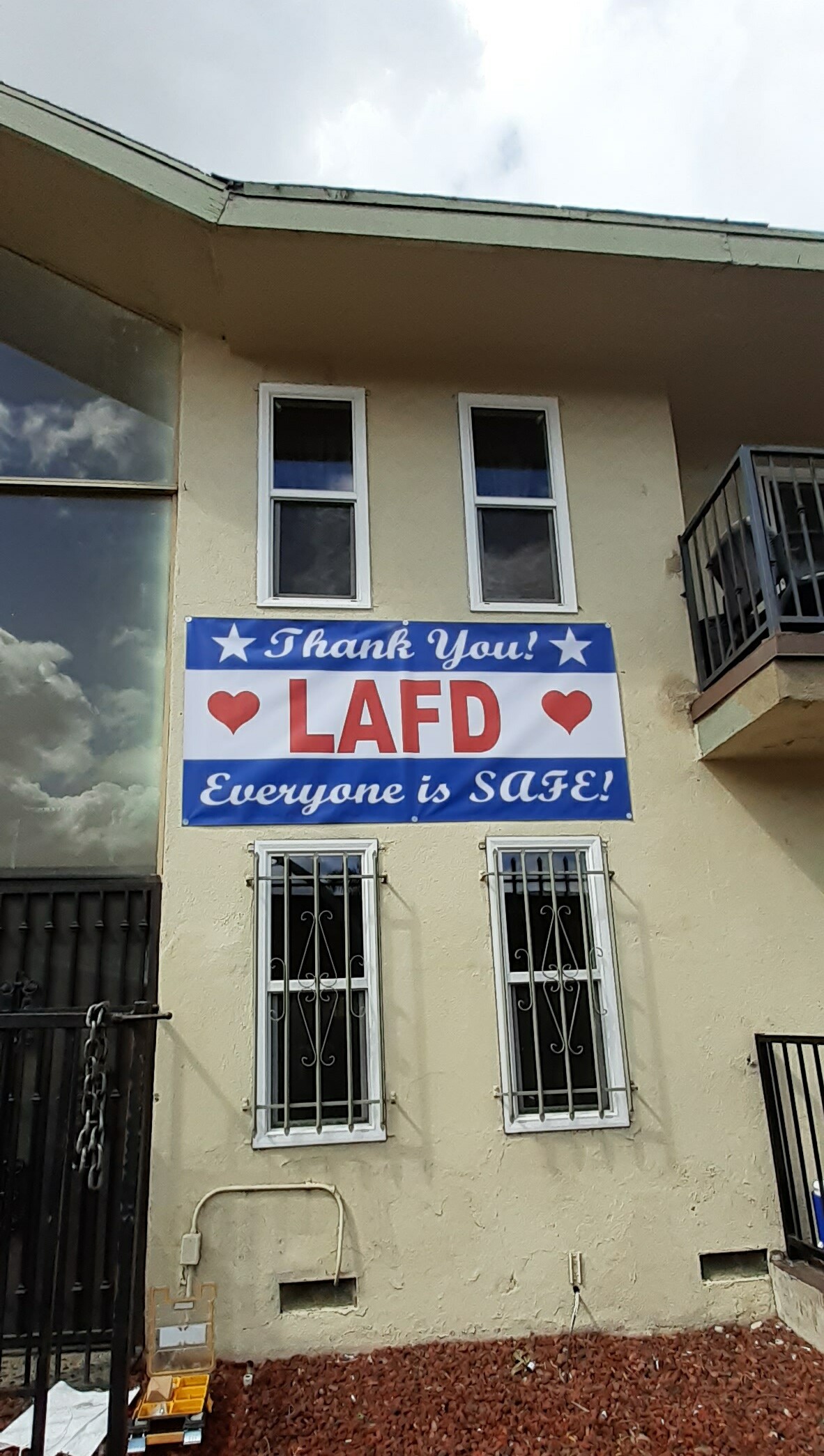 Banner on apartment building that reads "Thank You LAFD Everyone is SAFE."