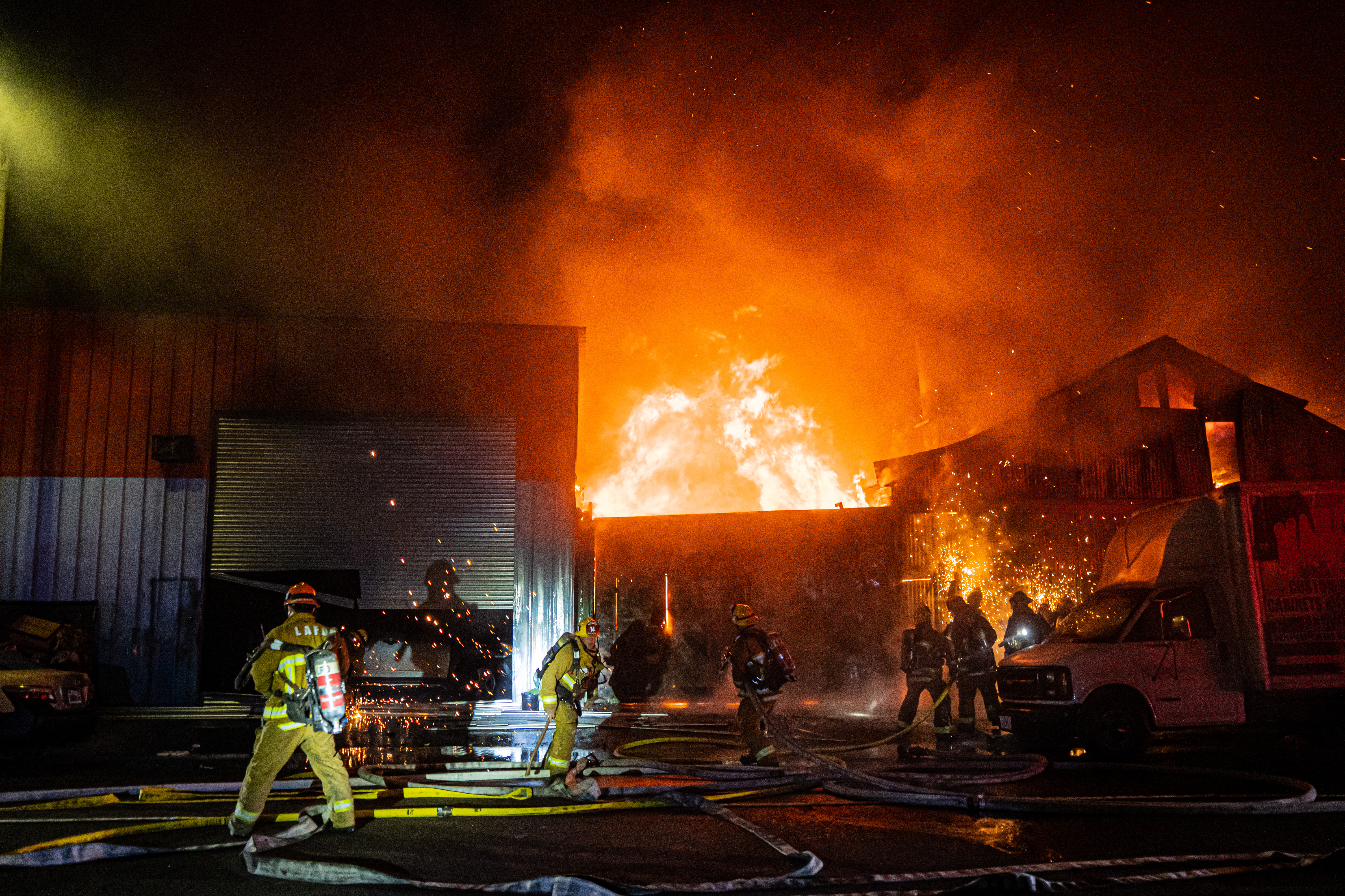 Nighttime view of commercial structure fire with flames through the roof.