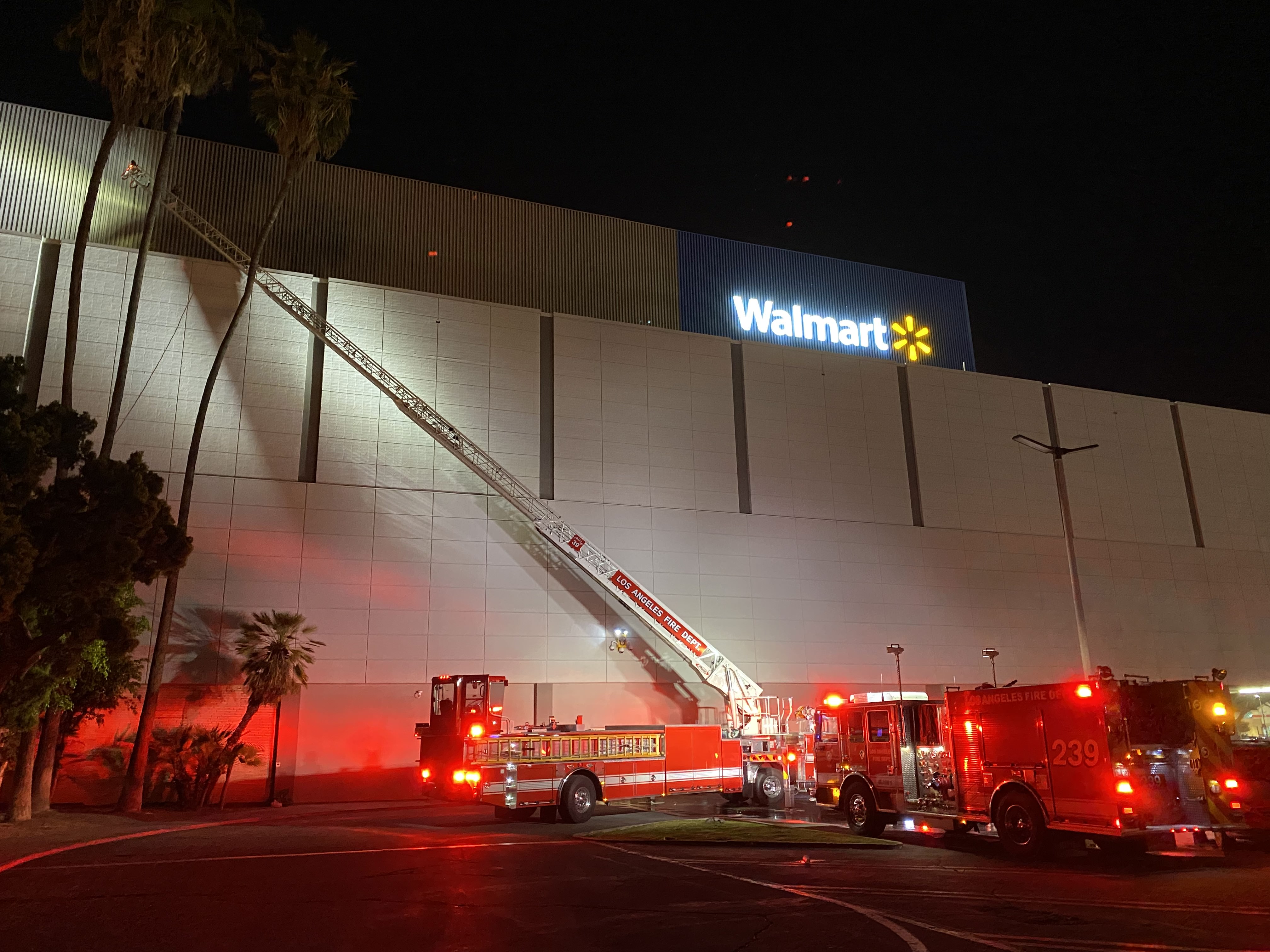 Fire truck with aerial ladder extended to roof of Walmart