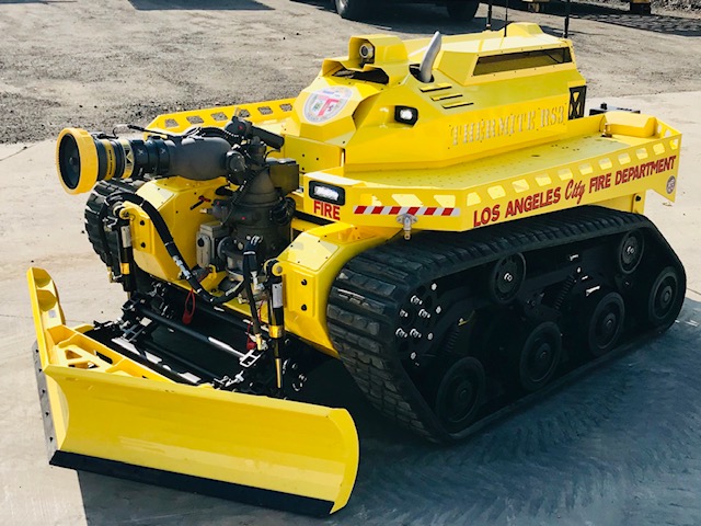 Yellow, robotic firefighting vehicle shown with dozer blades on the front